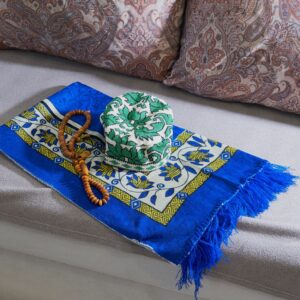 Muslim prayer essentials. Skullcap, prayer mat, and beads on sofa