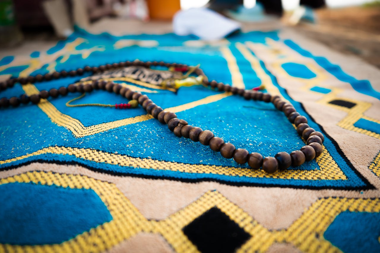 Detailed view of wooden prayer beads lying on a vibrant patterned rug.